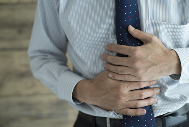 みぞおちをおさえる男性