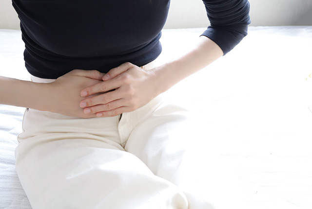 お腹をおさえる女性